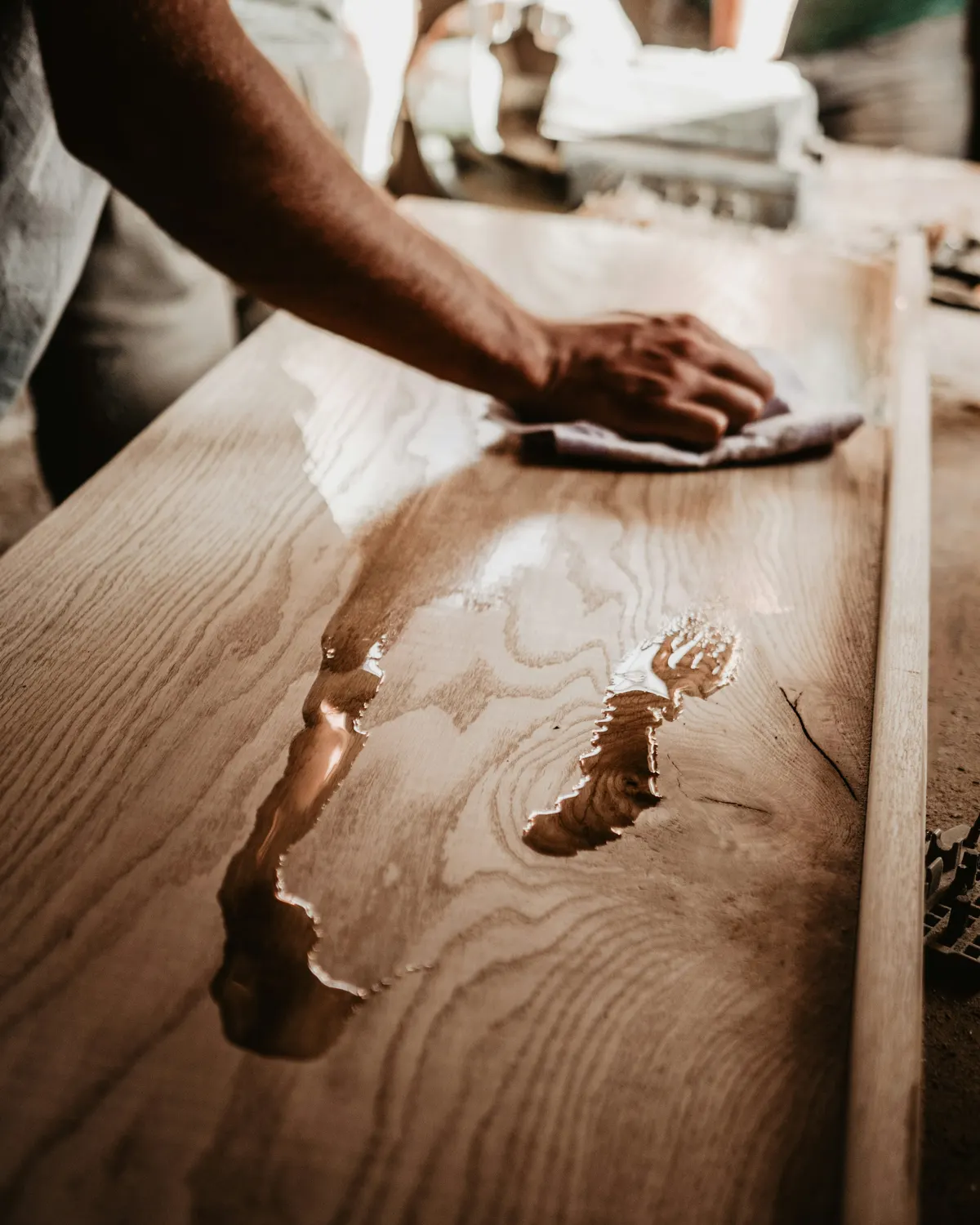 A hand rubbing oil finish into a timber top