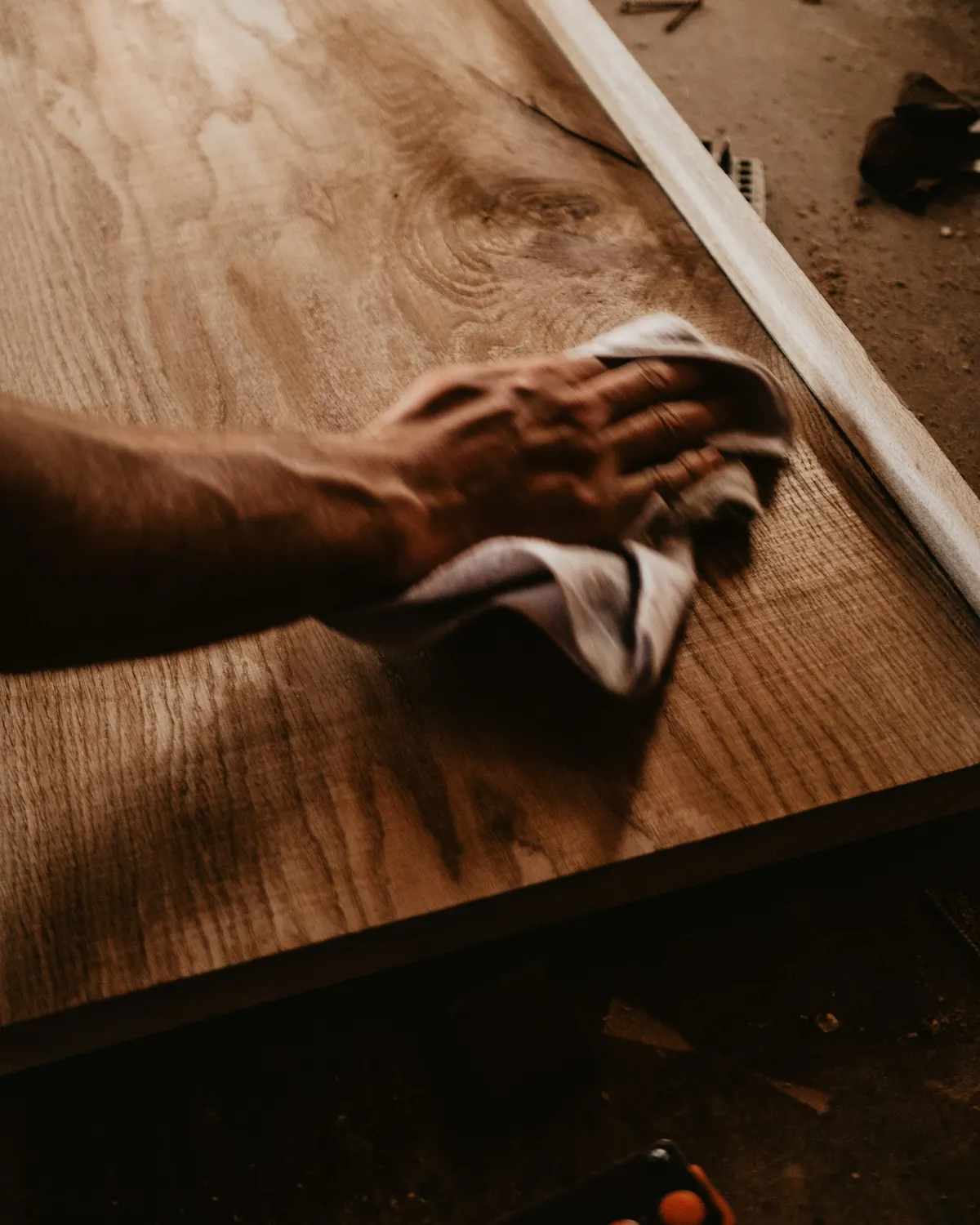 A finisher polishing a walnut top by hand